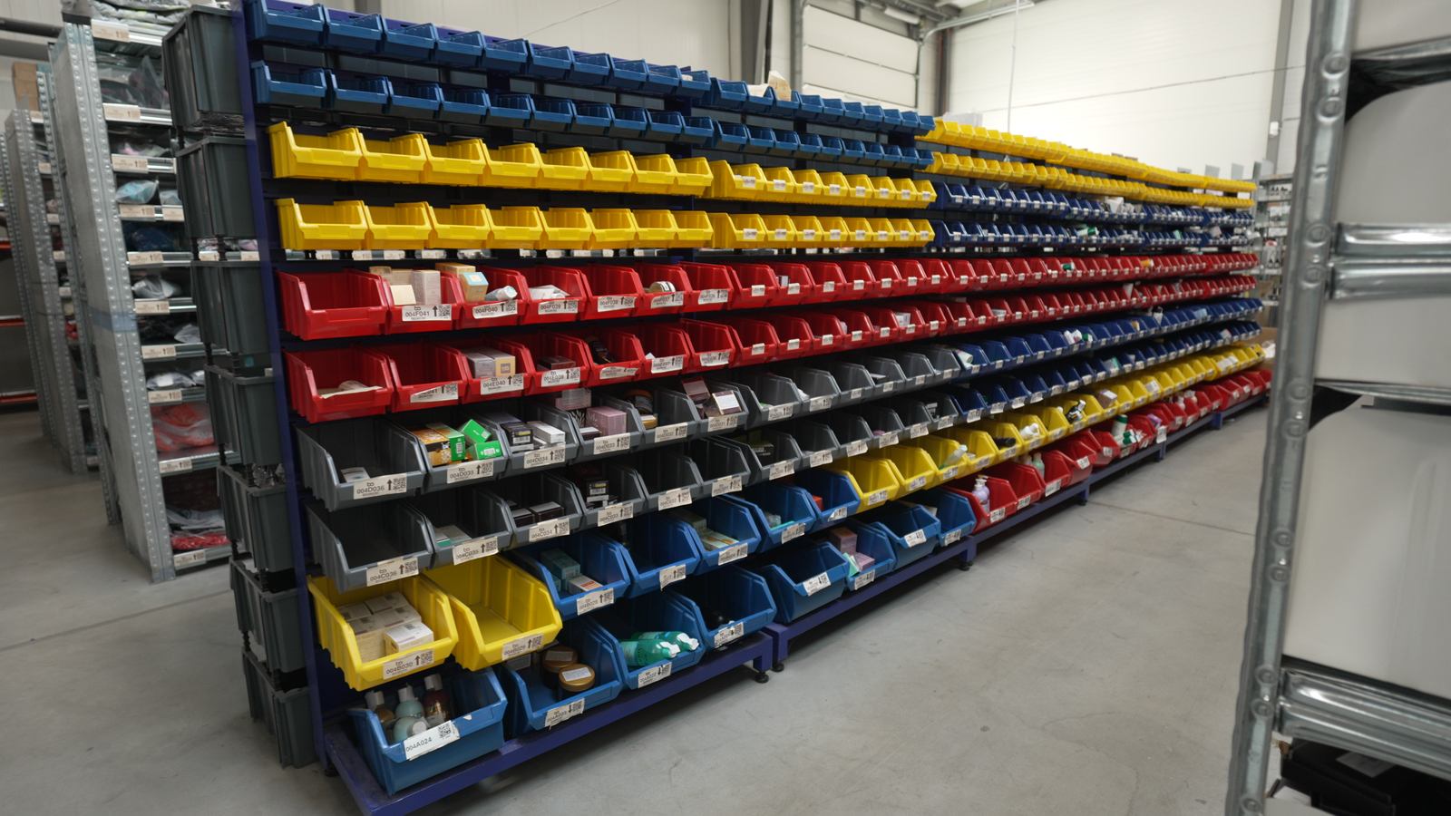 Estantería larga con cajas de colores con productos pequeños en un almacén de fulfillment de BigArena